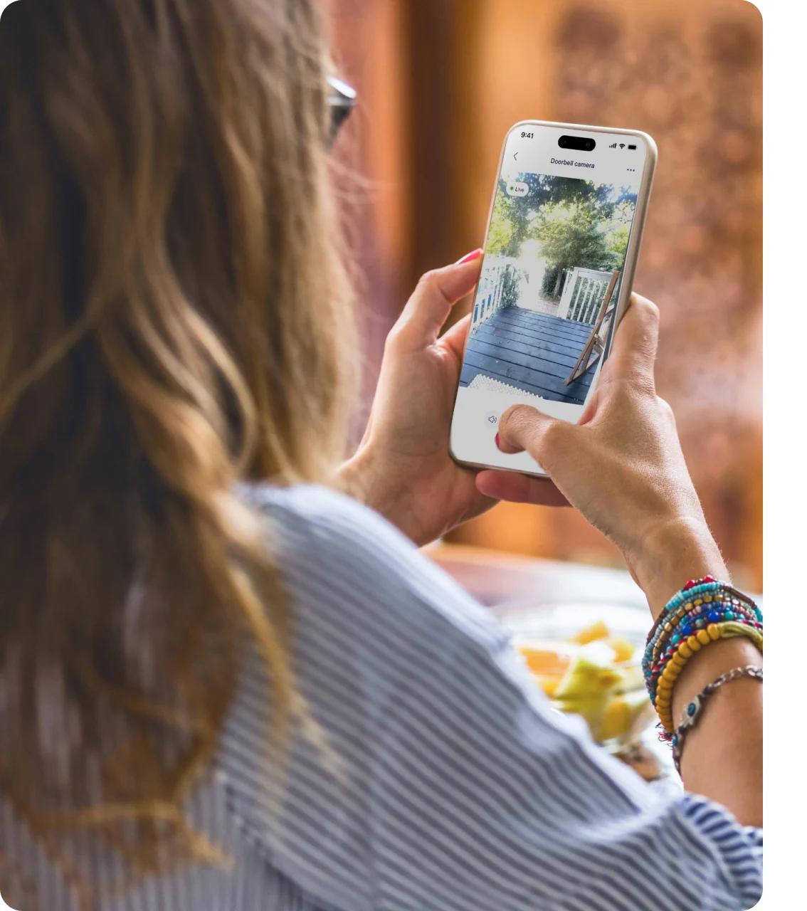 A woman reviews TELUS Doorbell camera footage on the TELUS SmartHome+ app while on a work from home lunch break. 