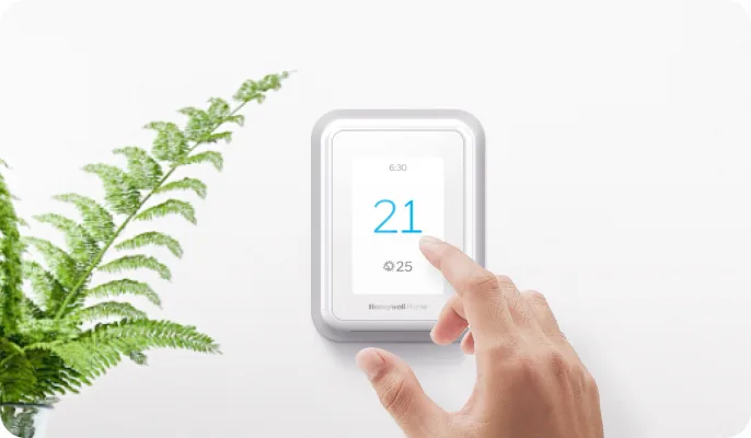 A hand adjusts a smart thermostat. 