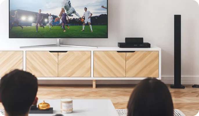 A couple watch sports on their TV in the living room. 