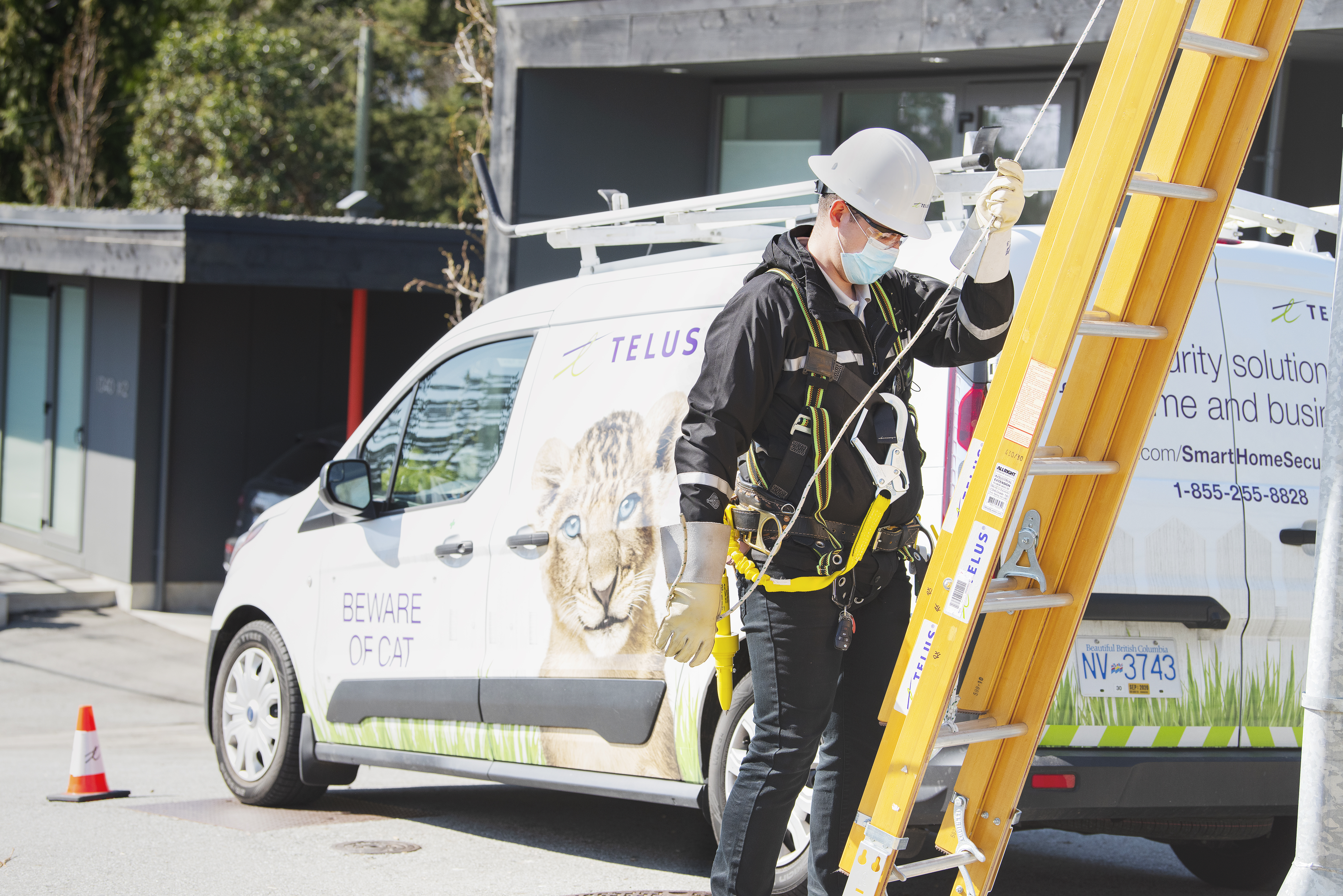 A TELUS technician preparing to climb a ladder