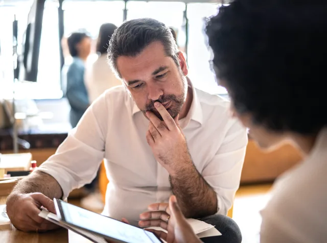 A person looking at a digital tablet held by their colleague