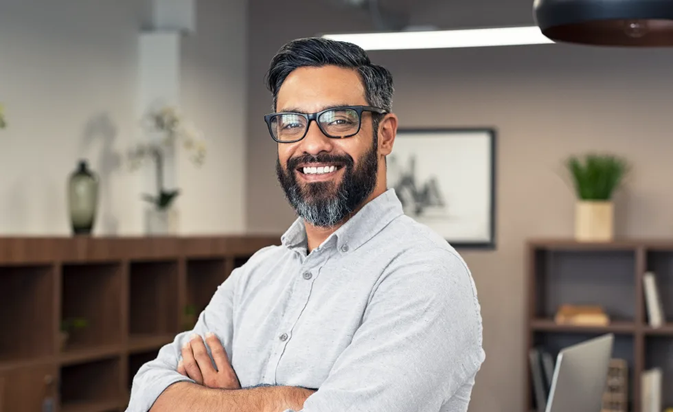 Man (Virtual CIO) wearing glasses, smiling, with arms folded