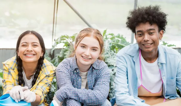 Three youths smiling while seated in a garden