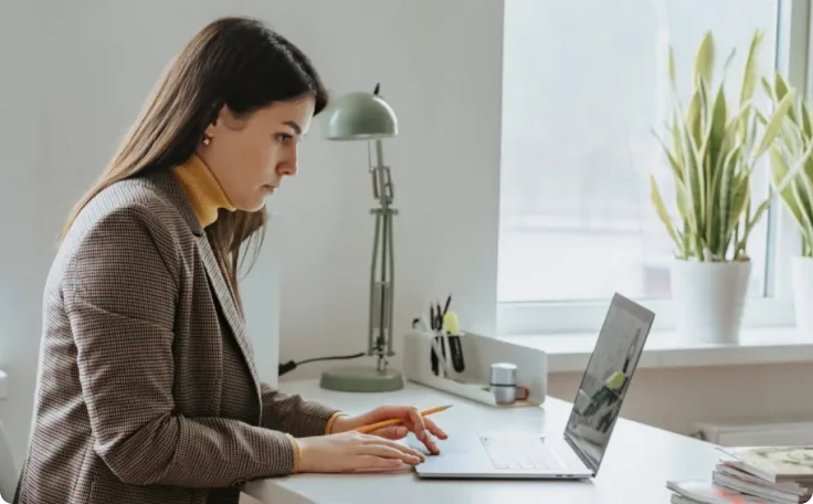 An individual sitting at a desk and working on their laptop.