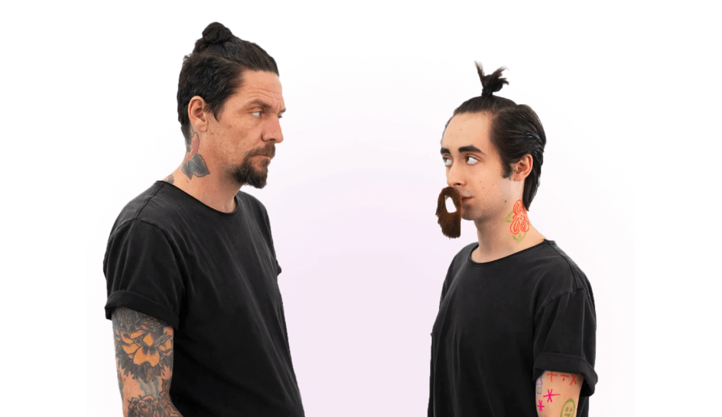 A man, wearing a black shirt with a goatee, stares at another man trying to pass as him by wearing a similar outfit and a fake beard.