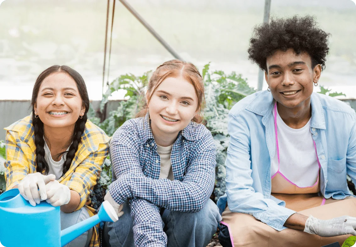 Three youths smiling while seated in a garden