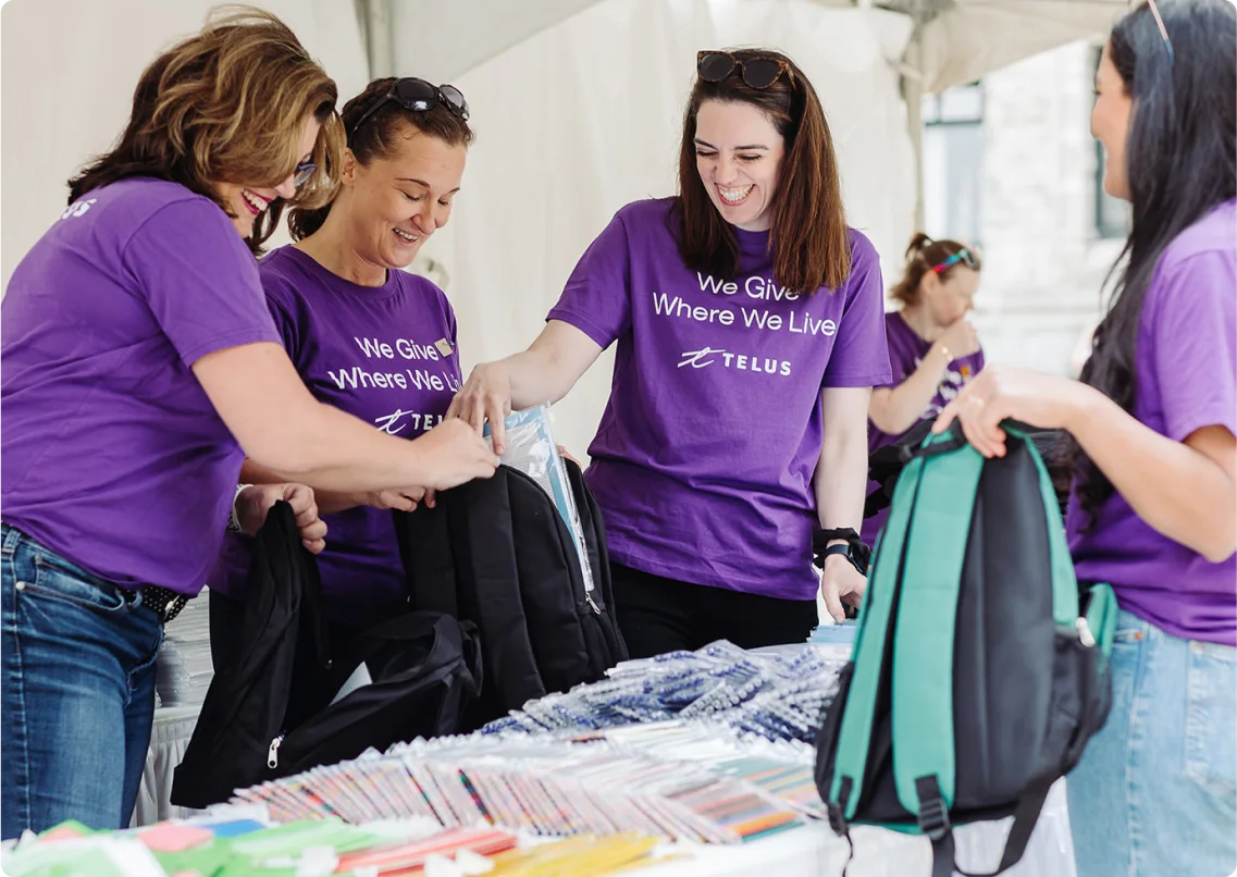 TELUS team members filling backpacks with essential school supplies.