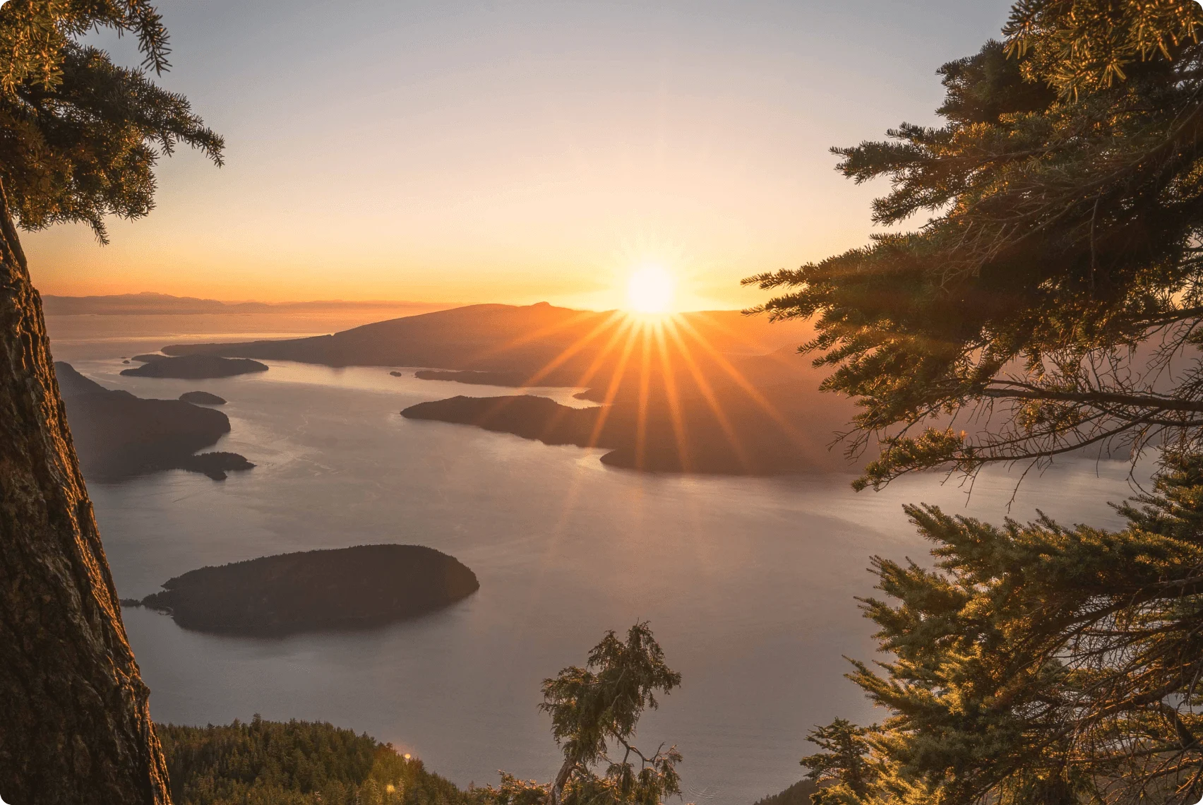 A landscape photo of Howe Sound and surrounding mountains at sunset.