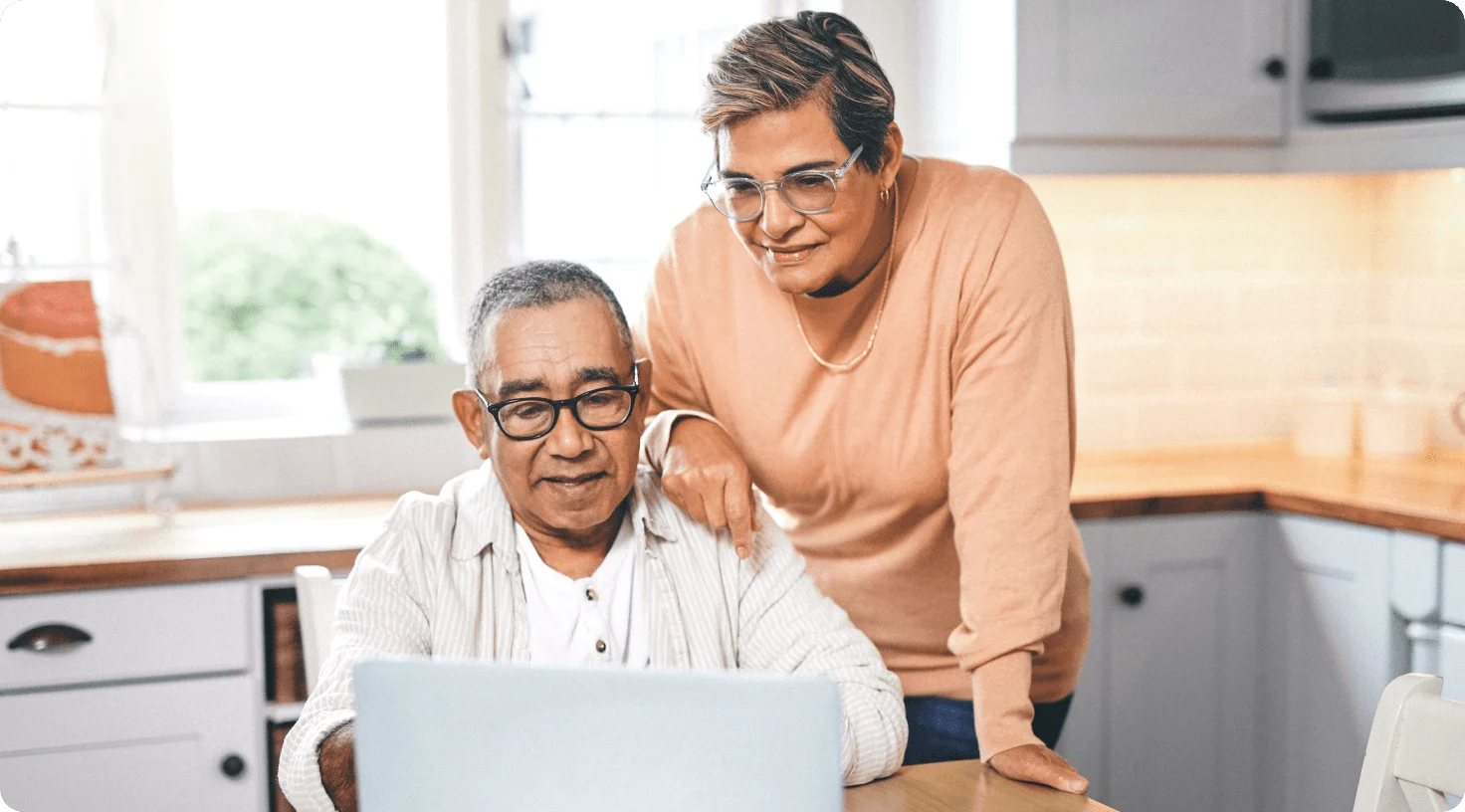 A senior couple viewing a laptop at their kitchen table