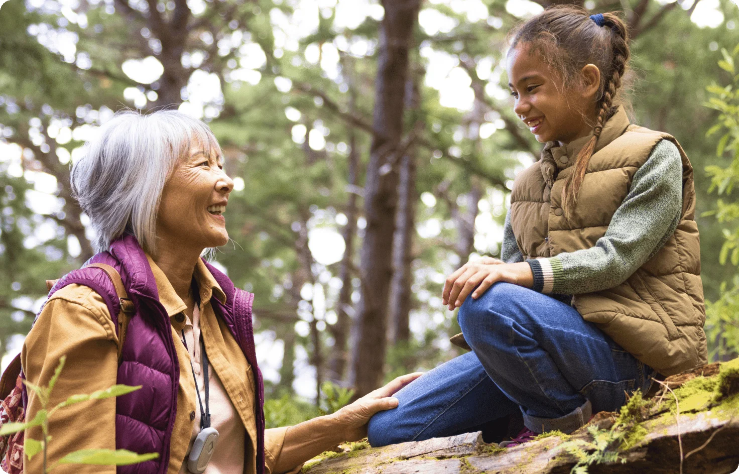 An older woman chatting with a youth in a forest