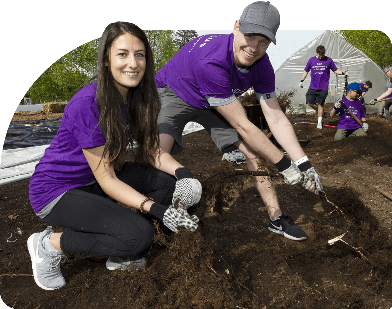 TELUS team members pulling weeds from a plot of land in a community garden.